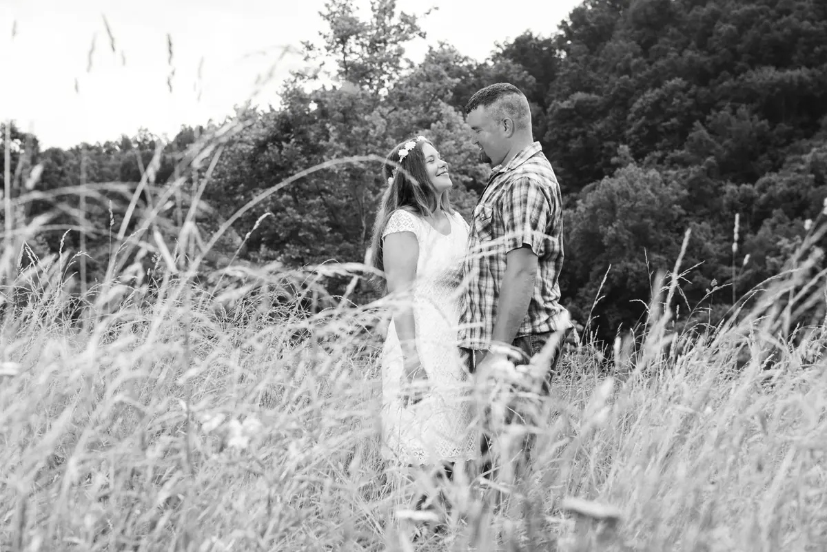 Black-and-white portrait of a couple together in tall meadow grass