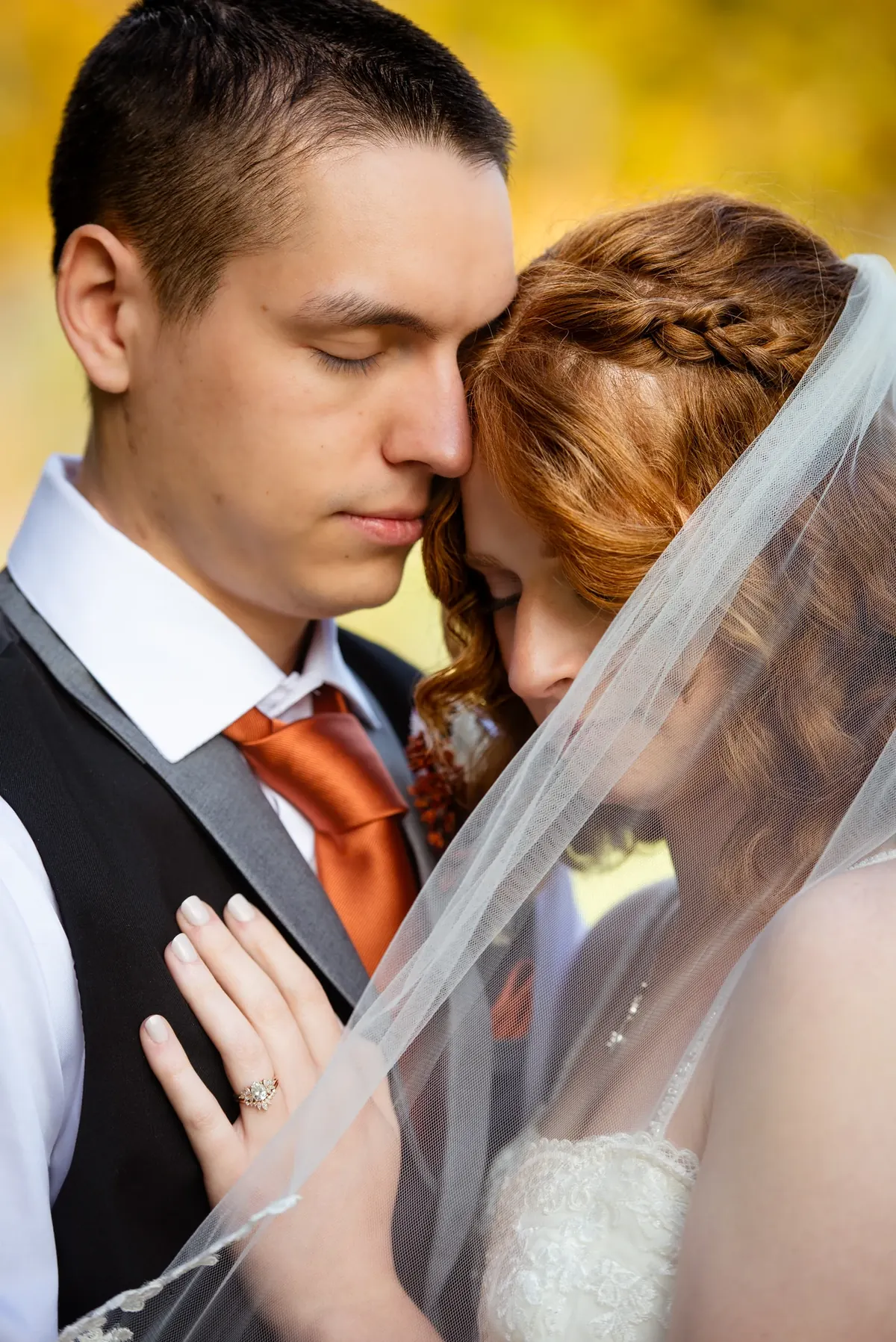 Close-up of a couple leaning together beneath a bridal veil