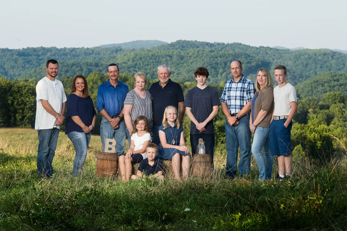 Extended family gathered in a meadow with wooded hills behind them