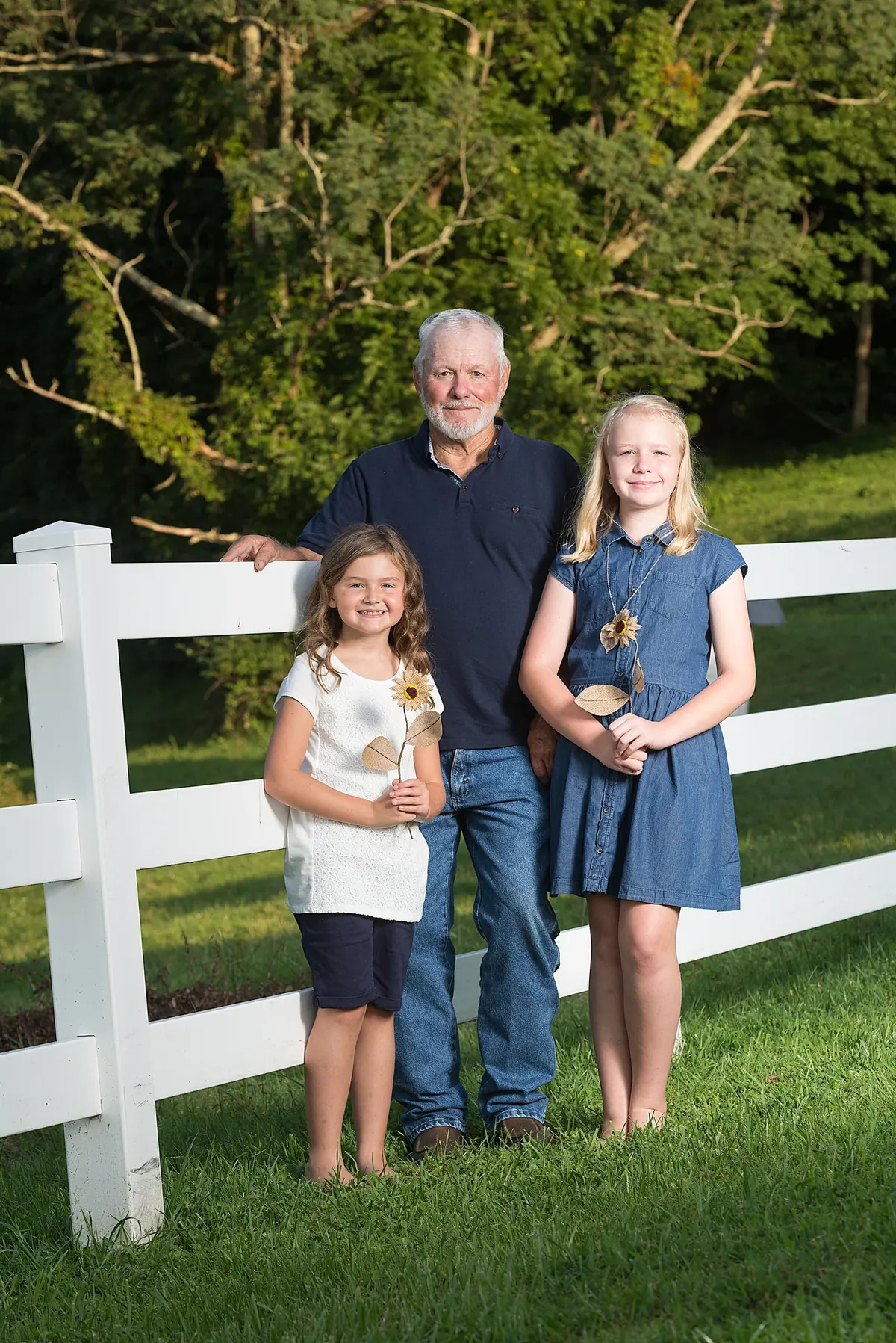 Adult and two children standing beside a white fence