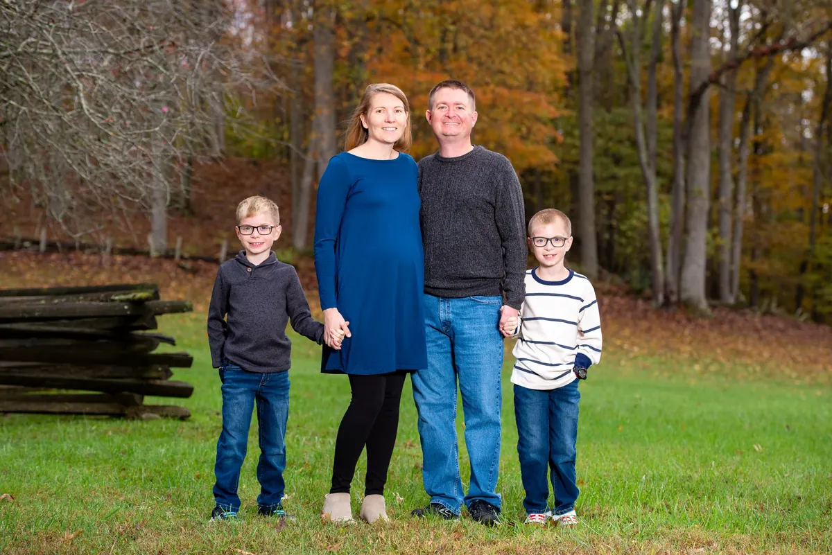 Family of four holding hands outdoors in autumn