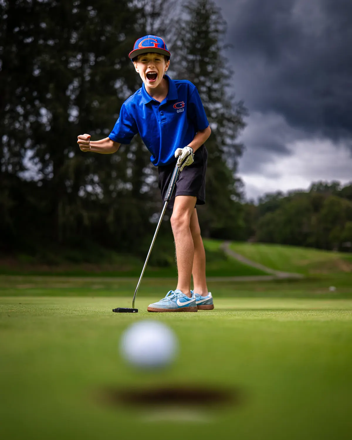 Golfer reacting to a putt on a green, with the ball in the foreground